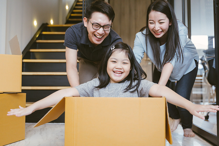 Girl playing in a moving box with her parents after purchasing a home with Your Home Sold Guaranteed Realty.